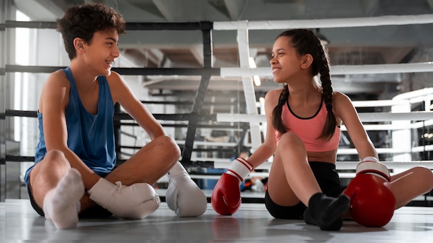 Free photo full shot kids sitting at gym