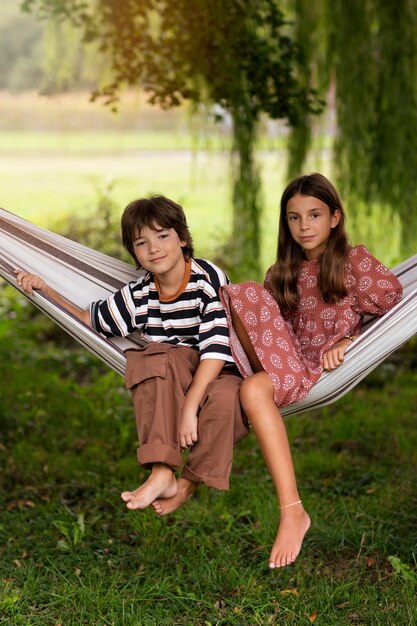 Full shot kids sitting in hammock