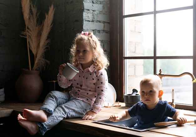 Full shot kids sitting in the kitchen