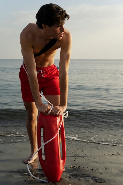 Free photo full shot lifeguard with lifesaving buoy