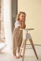 Free photo full shot little girl posing with chair