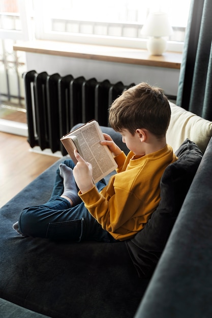 Full shot little kid reading bible at home