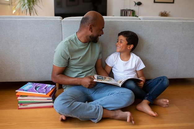 Full shot man and boy reading comics at home