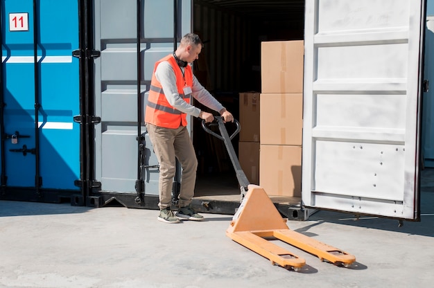 Full shot man carrying pallet truck