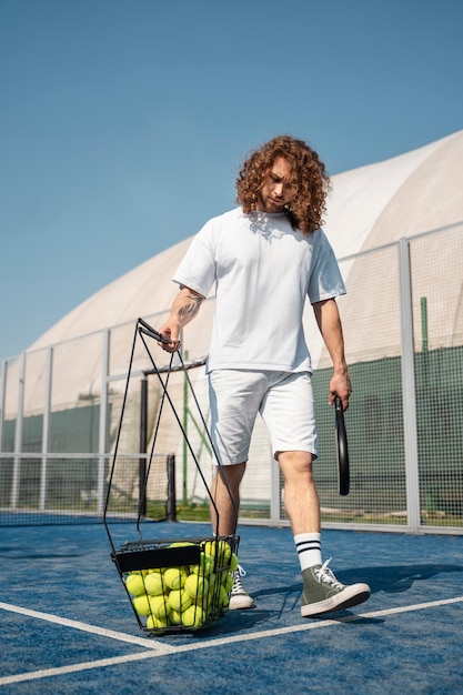 Full shot man carrying tennis balls