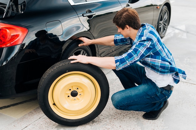 Full shot of man changing car tire