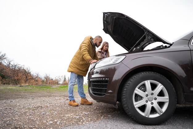 Full shot man checking car's engine