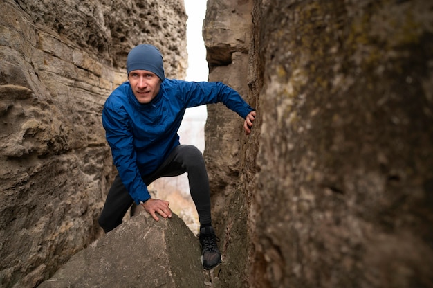 Free photo full shot man climbing through rocks