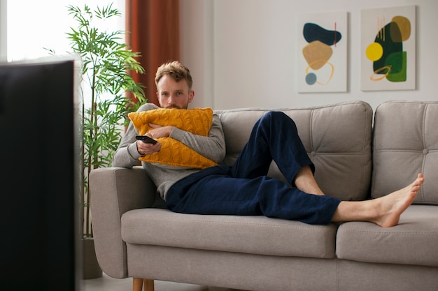 Полный кадр мужчина на диване смотрит телевизор