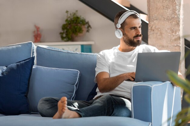 Full shot man on couch with laptop