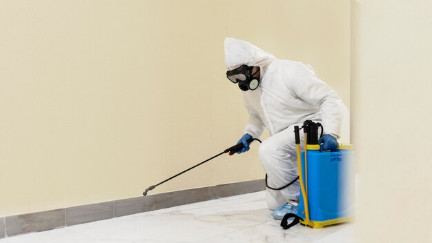 Full shot man disinfecting wall