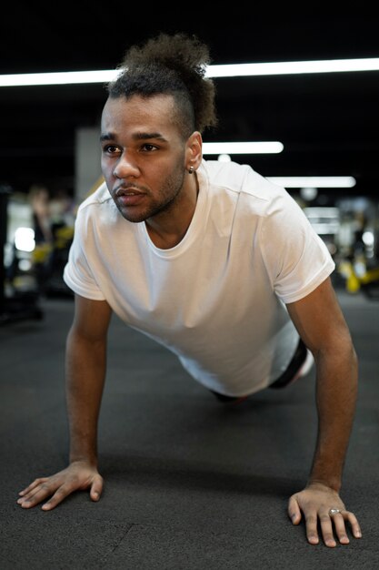 Full shot man doing burpee at gym