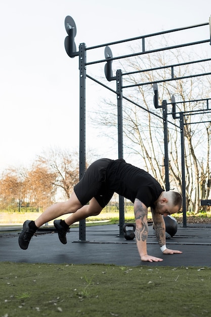 Full shot man doing burpees outdoors