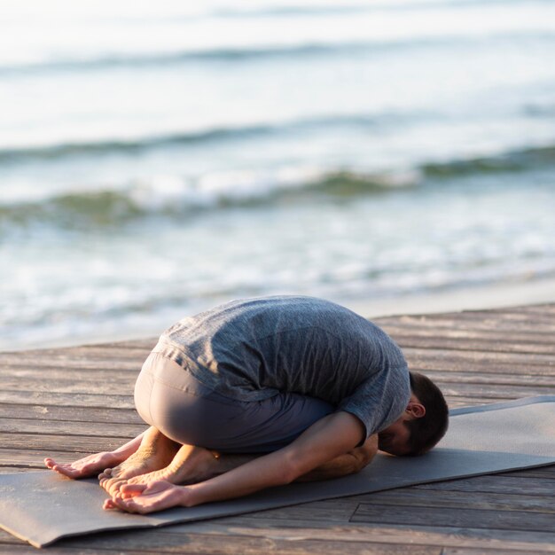 Full shot man doing child pose outside