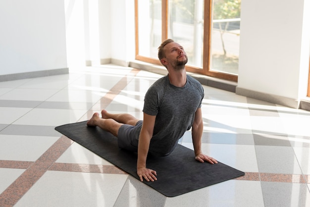 Full shot man doing cobra pose indoor