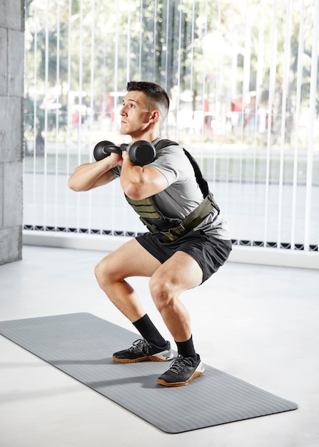 Uomo pieno del colpo che fa squat con il dumbbell