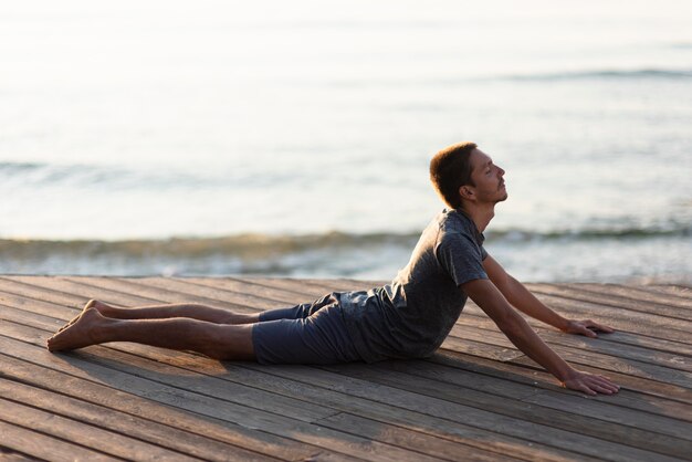 Full shot man doing upward facing dog near sea