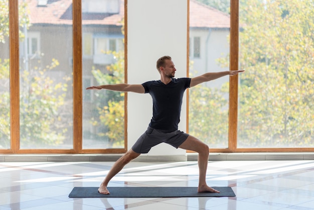 Full shot man doing warrior pose indoor