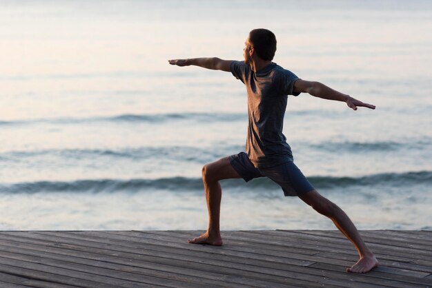 Free photo full shot man doing warrior pose outside