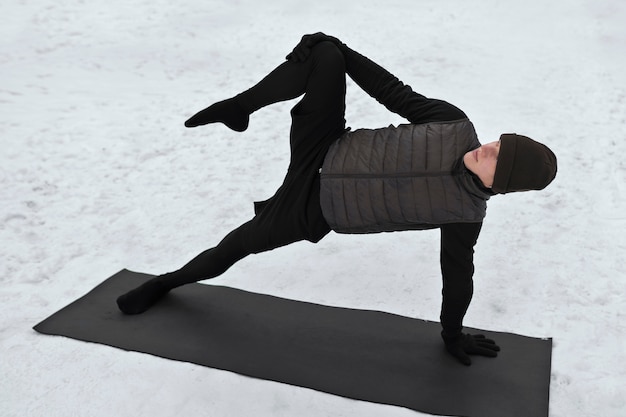 Foto gratuita uomo a tutto campo che fa yoga quando fa freddo
