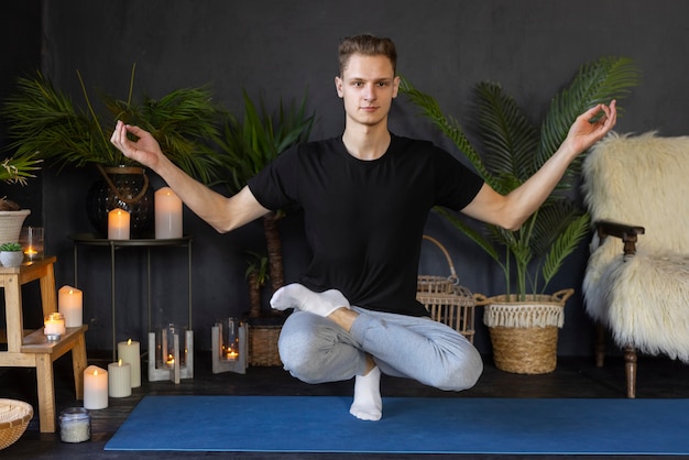 Foto gratuita uomo a tutto campo che fa yoga al chiuso