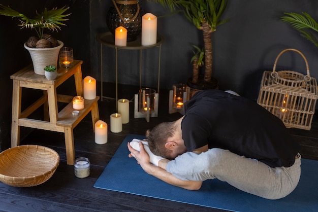 Foto gratuita uomo a tutto campo che fa yoga al chiuso