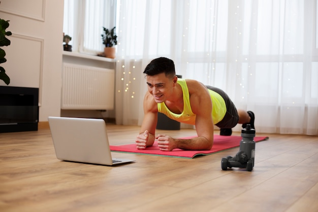 Foto gratuita uomo del colpo pieno che fa yoga sulla stuoia