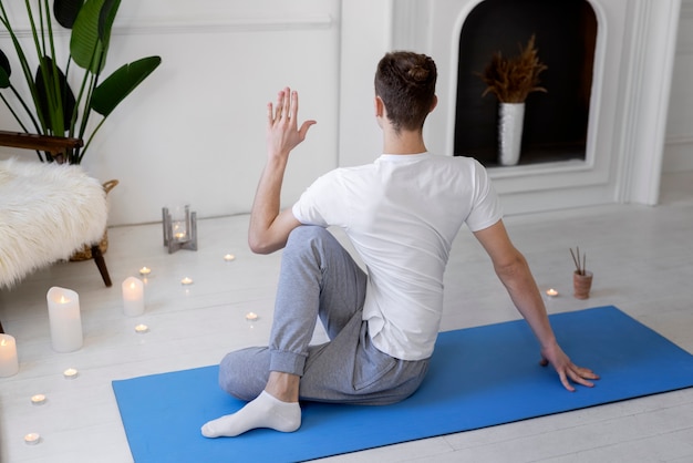 Free photo full shot man doing yoga on mat