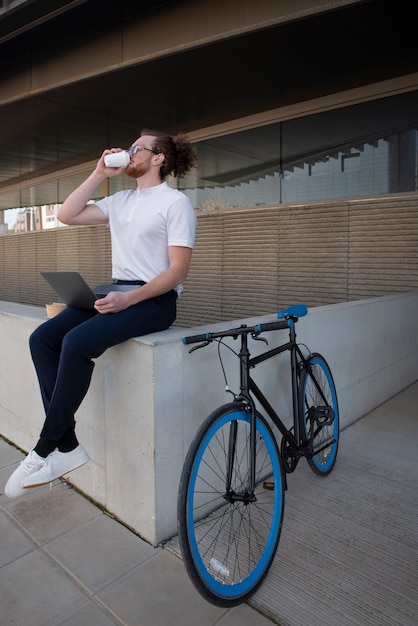 屋外でコーヒーを飲むフルショットの男