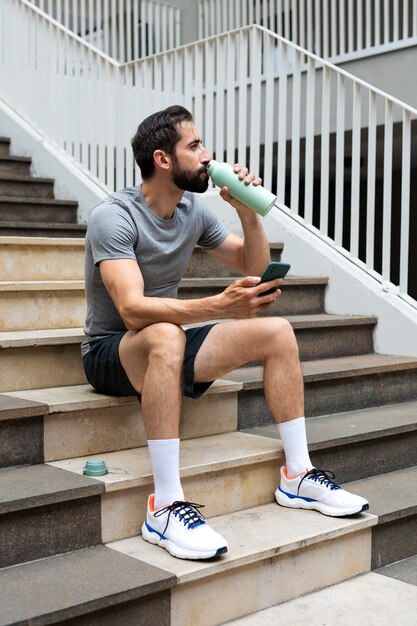 ボトルから水を飲むフルショットの男