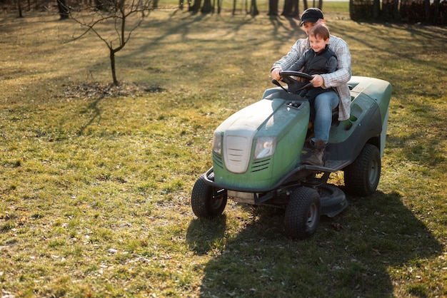 Full shot man driving lawn mower outdoors