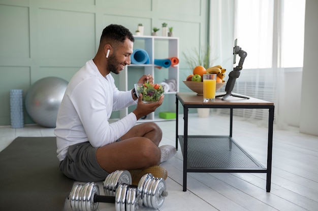 Free photo full shot man eating eating salad