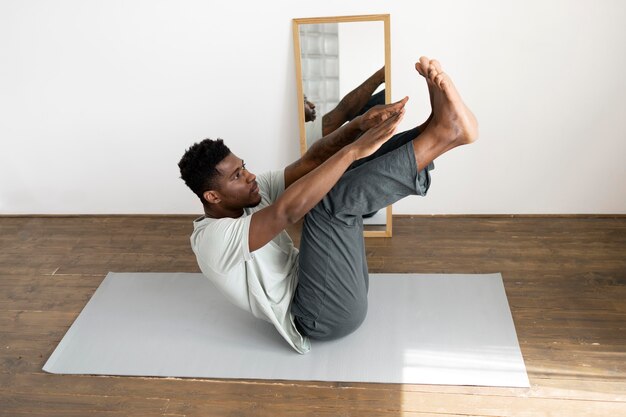 Full shot man exercising on mat