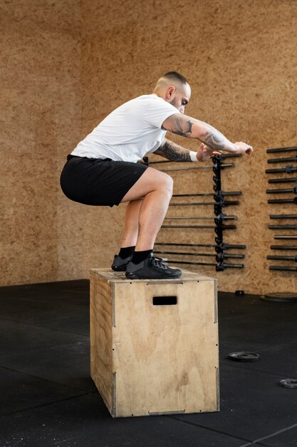 ジムでボックスで運動するフルショットの男