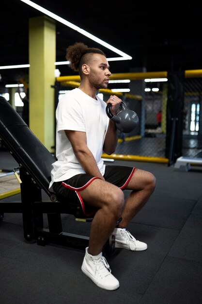 Full shot man exercising with kettlebell at gym