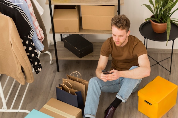 Free photo full shot man on floor with smartphone