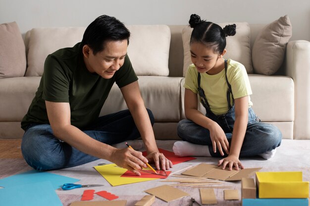 Full shot man and girl cutting paper