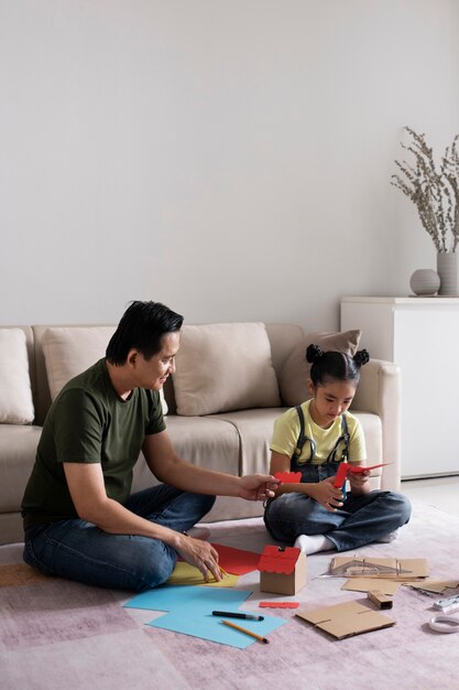 Full shot man and girl doing crafts indoors