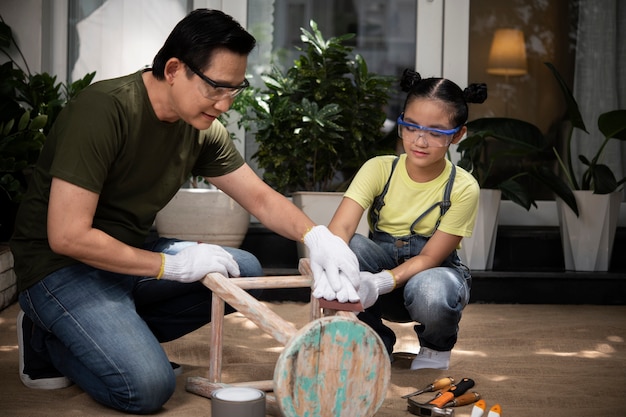 Free photo full shot man and girl scrubbing wooden chair