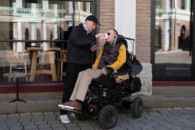 Full shot man helping disabled friend drink