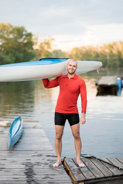 Full shot man holding canoe on shoulder