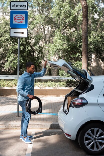 Full shot man holding car cable