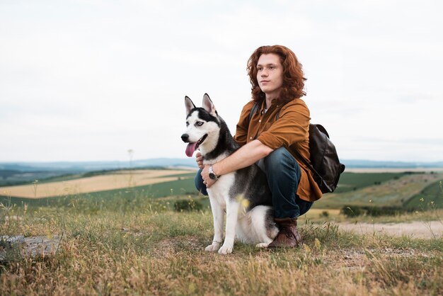 Free photo full shot man holding dog in nature