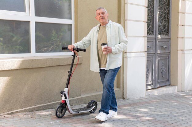 Full shot man holding scooter