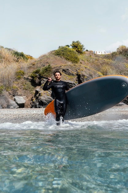 Full shot man holding surfboard