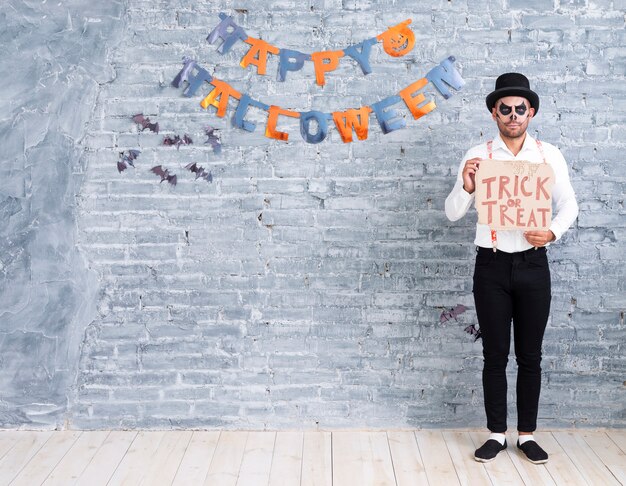 Full shot man holding trick or treat sign for halloween