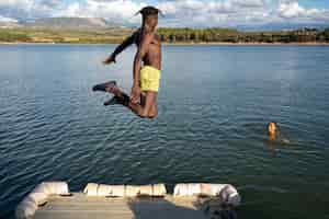 Foto gratuita uomo del colpo pieno che salta nel lago