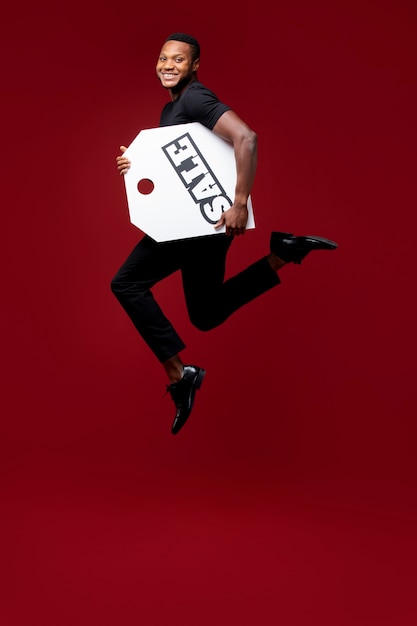 Free photo full shot man jumping with sale tag