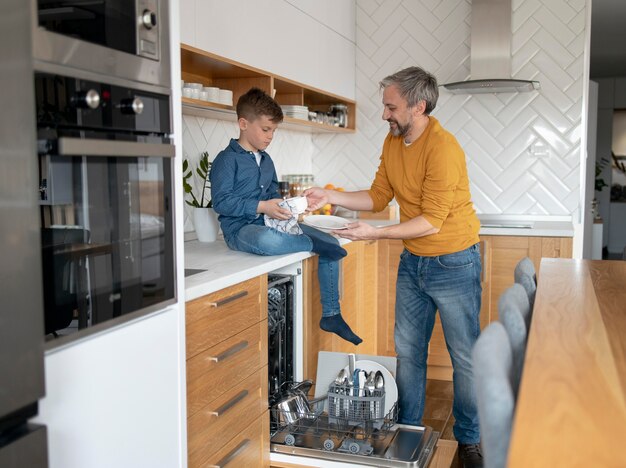 full shot man and kid cleaning dishes