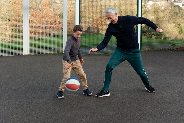 Full shot man and kid playing basketball